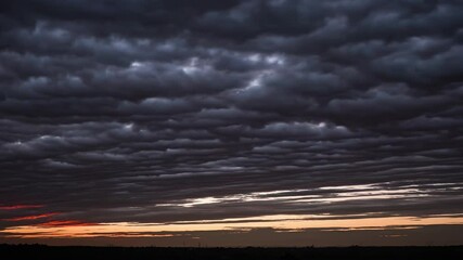Wall Mural - Vibrant altocumulus clouds racing across fiery red and orange sky during intense sunset, creating dramatic atmospheric panorama with golden light and dynamic cloudscape