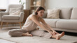 © Olia - Lifestyle-based relief for restless legs syndrome depicted by woman doing leg stretches to reduce nighttime discomfort