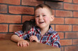 © New Africa - Little boy with his pet rat at wooden table indoors