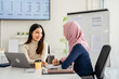 © Fahng - Multiracial young female employees work on laptop discuss business cooperation ideas at meeting together, businesswomen brainstorm collaborating using laptop computer at office briefing