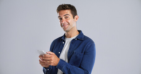 Poster - Portrait, happy man and typing with mobile in studio for social media or text on white background. Phone, smile and person with message on app for download, network and blog post with mockup space
