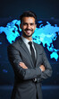 © panophotograph - A Latinx male business leader in a sharp grey suit, his arms crossed in front of a digital world map