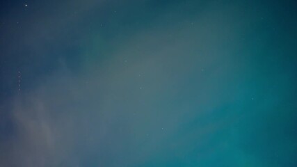 Wall Mural - early evening aurora northern lights in a light blue sky flashing behind drifting clouds with big di