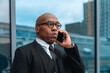 © Iryna - Businessman engaged in a phone call outside a modern office building in an urban setting during the afternoon