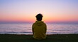 © Tida - Serene Sunset by the Ocean - Person sitting on the grass, facing a beautiful ocean sunset. Peaceful and tranquil scene