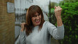 © Krakenimages.com - Senior hispanic woman celebrating with joy in a city street, capturing a vibrant moment of happiness and success in an urban outdoor setting.