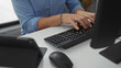 © Krakenimages.com - Man typing on keyboard in modern office setting with focus on hands and technology, wearing casual blue shirt, busy in indoor workplace environment.