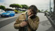 © Krakenimages.com - Young man with tousled hair asleep on a city street holding a coffee, wearing a brown jacket, creating a relaxed yet tired urban vibe under the cloudy sky.