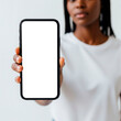 © Marlon - Close-up of a large smartphone's bright white screen held by a Black woman against a white background.