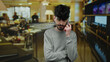 © Krakenimages.com - Young man with beard talking on smartphone in hotel bar surrounded by people and cozy lighting conveys casual ambiance and connection