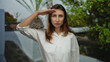 © Krakenimages.com - Woman saluting outdoors on a city street, young and focused, wearing a white shirt amidst urban greenery conveying a sense of pride and respect in a european cityscape.