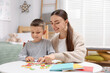 © New Africa - Dyslexia. Mother and her son learning letters at table indoors