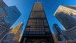 © lestari - A tall skyscraper is surrounded by other buildings against blue sky