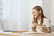 © SHOTPRIME STUDIO - Young girl interacting joyfully with a laptop at home, showcasing emotions of happiness and excitement in a bright, minimalistic environment
