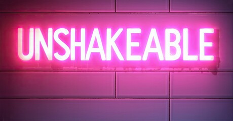 Aufkleber - Bright pink neon sign spells UNSHAKEABLE against tiled wall. Dark background emphasizes glowing letters, creating bold visual impact.