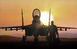 Air force pilot walking to jet fighter on airbase at sunset