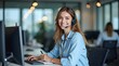 © Nathan - Smiling young woman with long hair wearing a headset, engaged in a customer service role at a modern office.