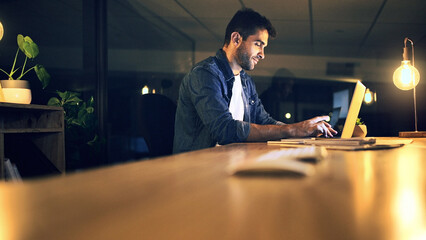 Poster - Laptop, night and typing with business man in office for deadline or feedback on creative report. Computer, desk and research with design employee in dark workplace for productivity at zero hour