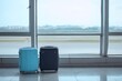 © Xiaoxiao - Light blue and navy blue suitcases on airport floor near windows overlooking tarmac, minimalist travel stock photo