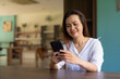 © Ranta Images - Woman sitting in library using phone