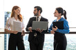 © Jack Tamrong - Businessman holding laptop and two female colleagues working together at high rise office balcony