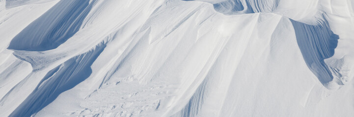 Wall Mural - Snow texture. Wind sculpted patterns on snow surface. Wind in the tundra and in the mountains on the surface of the snow sculpts patterns and ridges. Arctic, Polar region. Winter panoramic background.