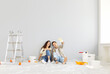 © Studio Romantic - Young and happy family couple, sitting on floor and dreaming about new home during renovation and painting walls. Showing joy and excitement about construction and home improvement.