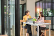 © panomporn - Two professional businesswomen are working on laptop computers sitting at desks in the office. Colleagues are happy and discussing the digital strategy of the Graph