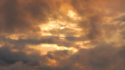 Wall Mural - The sun's disk shines through stratus cumulus clouds in the evening sky at golden hour aurora, changeable weather