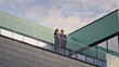 © stockbusters - Confident business people communicating at rooftop balcony. Man woman talking