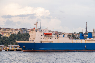 Poster - Cargo ship navigating the Bosphorus strait with city skyline in the background during late afternoon light
