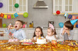 © New Africa - Children at table with tasty cake and different treats indoors. Surprise party