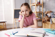 © New Africa - Dyslexia. Upset little girl reading book at table indoors