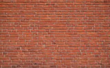 Uniform red brick wall providing a minimalist and textured background ideal for various design applications