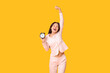 © Pixel-Shot - Beautiful young happy Asian woman in pajamas with alarm clock on yellow background