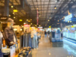 © pandaclub23 - blurry image showing the interior of a shopping mall. The scene is out of focus, with indistinct shops, lights, and people walking.