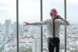 © Jack Tamrong - Handsome Caucasian male architect with safety helmet talking on phone standing in high rise office with skyscraper downtown view background