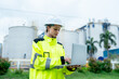 © narong - One petrochemical or gas factory worker or technician woman hold laptop for working with smiling in front of the factory.