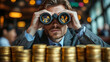 © Afan - Businessman with binoculars views market data behind stacks of coins in a cafe