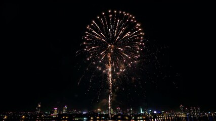 Wall Mural - fireworks in the sky over a city at night with a reflection in the water