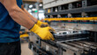 © Maksym - Industrial metal sheet bending process in progress, yellow-gloved hands adjusting the metal on the press brake, factory floor filled with metal sheets and manufacturing tools