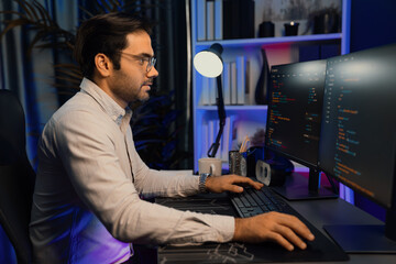 Working smart IT developer analyzing data software development on two pc screen, creating application program updated version online website page system online at neon light cyber office. Surmise.