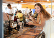 © JackF - Girl in flea market store look at silver decanter, antique gifts. Female buyer holds item in hands and examines product, makes purchase decision
