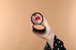 © New Africa - Beautiful woman with red lips looking in compact powder mirror on dark beige background, closeup