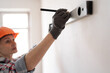 © Andrii Lysenko - home improvement and repair concept. Construction, builder and contractor with level measuring. handyman in hardhat holding spirit level