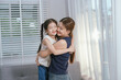 © Witoon - An Asian mother and daughter sit together indoors, smiling and bonding over a book, enjoying digital learning and joyful family time.