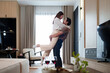 © Pichsakul - Asian Couple Embrace Romance in Home Setting Joyful Adult Man Holds Woman in Arms Love and Happiness Romantic Moment Indoors Relationship Goals