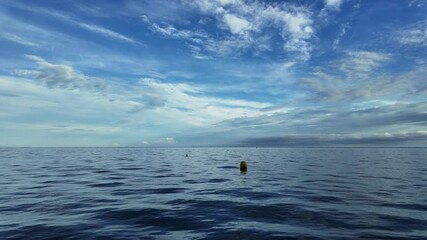 Wall Mural - Open calm ocean view under dramatic blue sky with scattered clouds and distant land on horizon