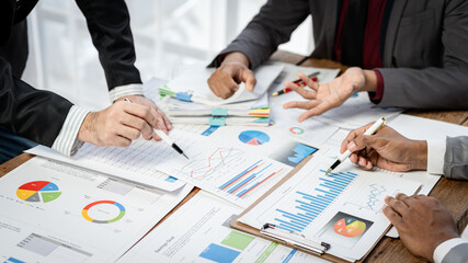 Fototapete - Three people are sitting at a table with papers and pens, discussing