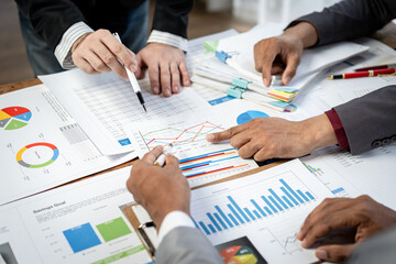 Fototapete - A group of people are working on a project, with one person pointing at a graph